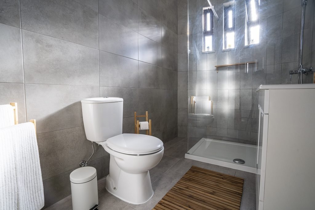 Clean bathroom at Wooden accents and neat, bright twin beds at Ericeira Paradise Guest House and Suites