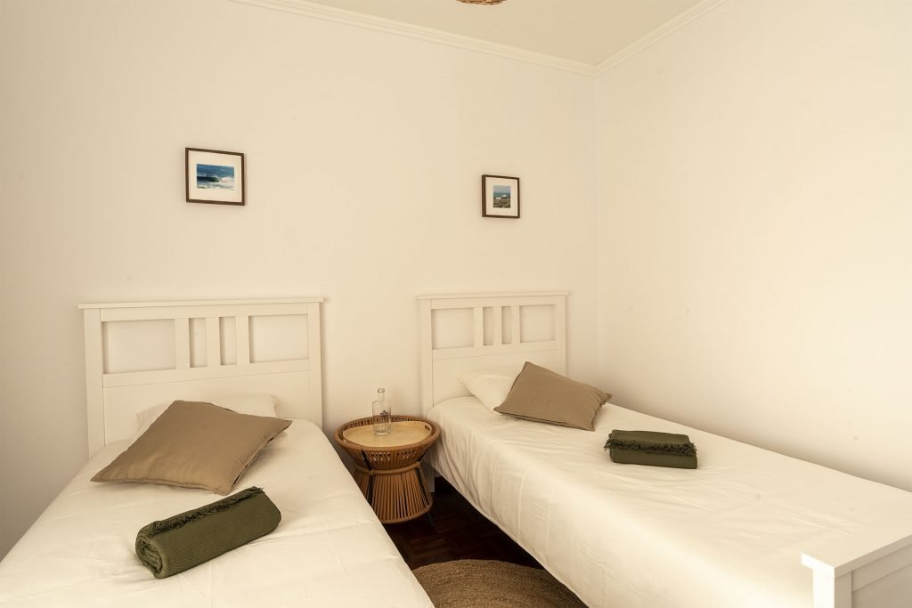 Ericeira Paradise Guest House twin room with wooden table, beige pillows, clean sheets and freshly folded towels