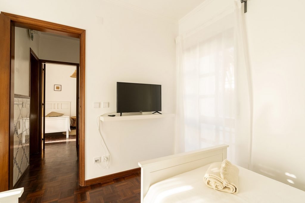 Brightly colored bedroom Wooden accents and neat, bright twin beds at Ericeira Paradise Guest House and Suites